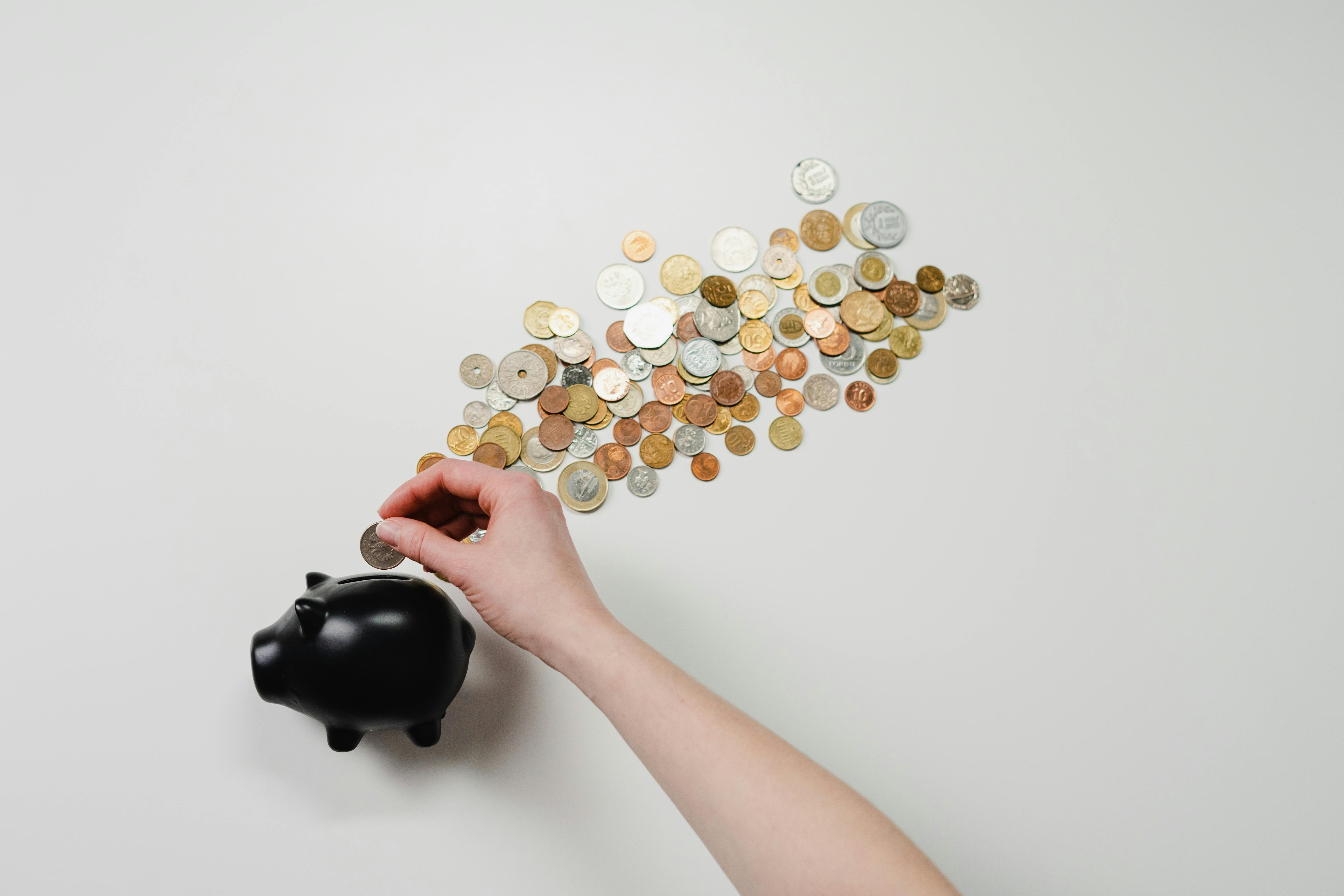 Stacks of coins next to a calculator on a white surface