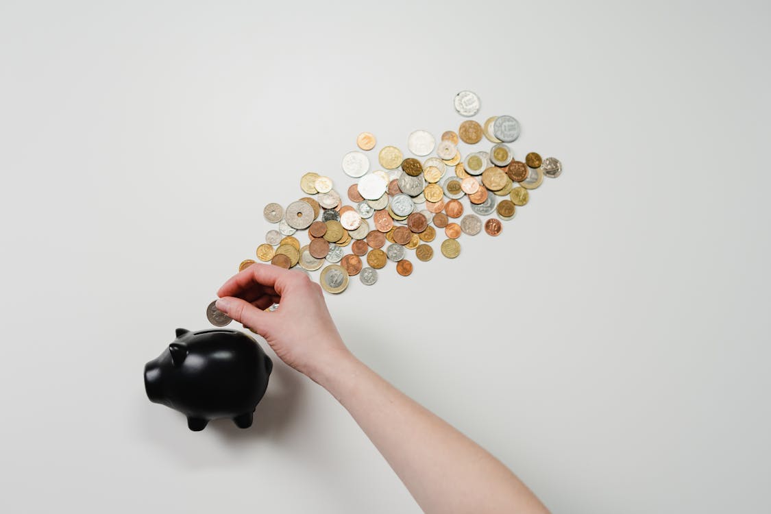 Free Person Putting Coin in a Piggy Bank Stock Photo