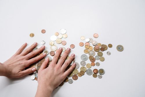Free Hands arranging a variety of international coins on a neutral light background. Stock Photo