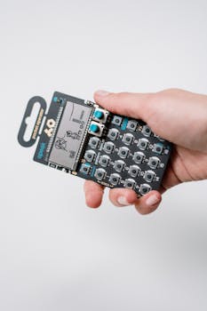 A handheld pocket synthesizer in someone's grasp, showcasing retro electronic design.