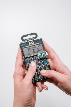 Close-up of hands holding a Pocket Operator, showcasing its compact and retro design.
