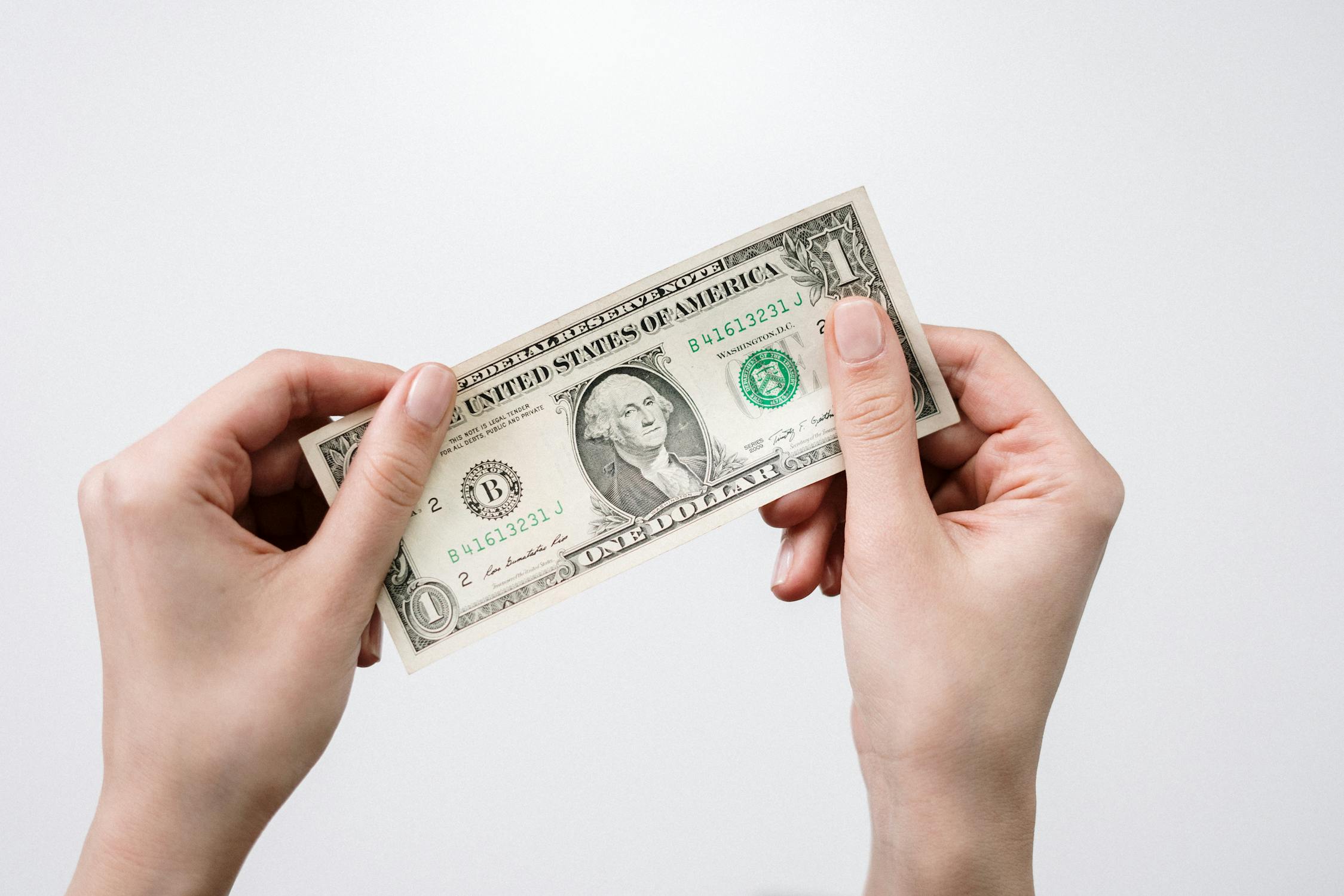 Hands holding a one dollar bill on a white background