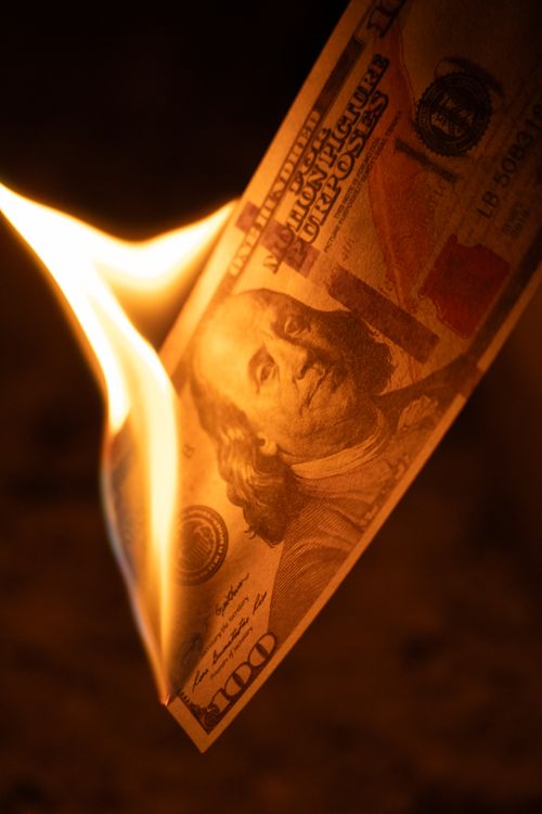Free Close-up image of a hundred dollar bill burning, symbolizing economic loss. Stock Photo