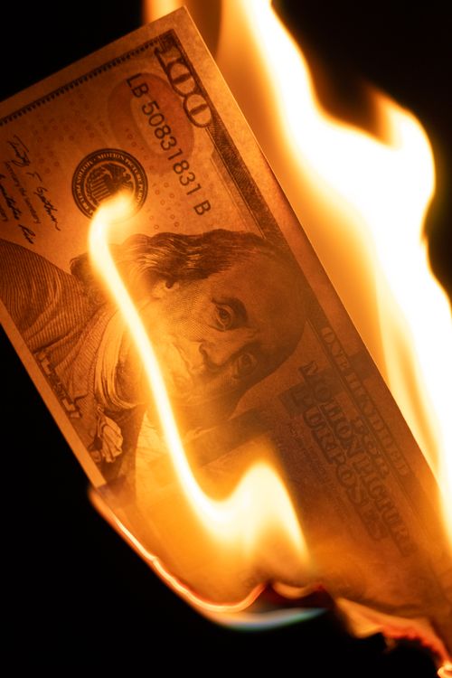 Free Close-up of a burning $100 bill, symbolizing financial loss and economic instability. Stock Photo
