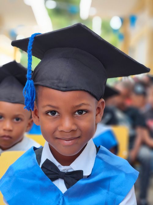 Free Smiling child in graduation cap and gown at a school ceremony, celebrating achievement. Stock Photo