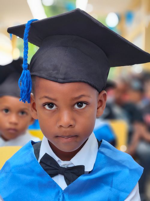 Free A young boy wearing a graduation cap and gown, focused and serious at a school ceremony. Stock Photo