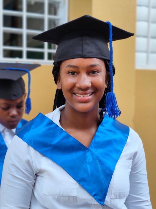 Free Smiling graduate in cap and gown with blue sash at a ceremony. Stock Photo