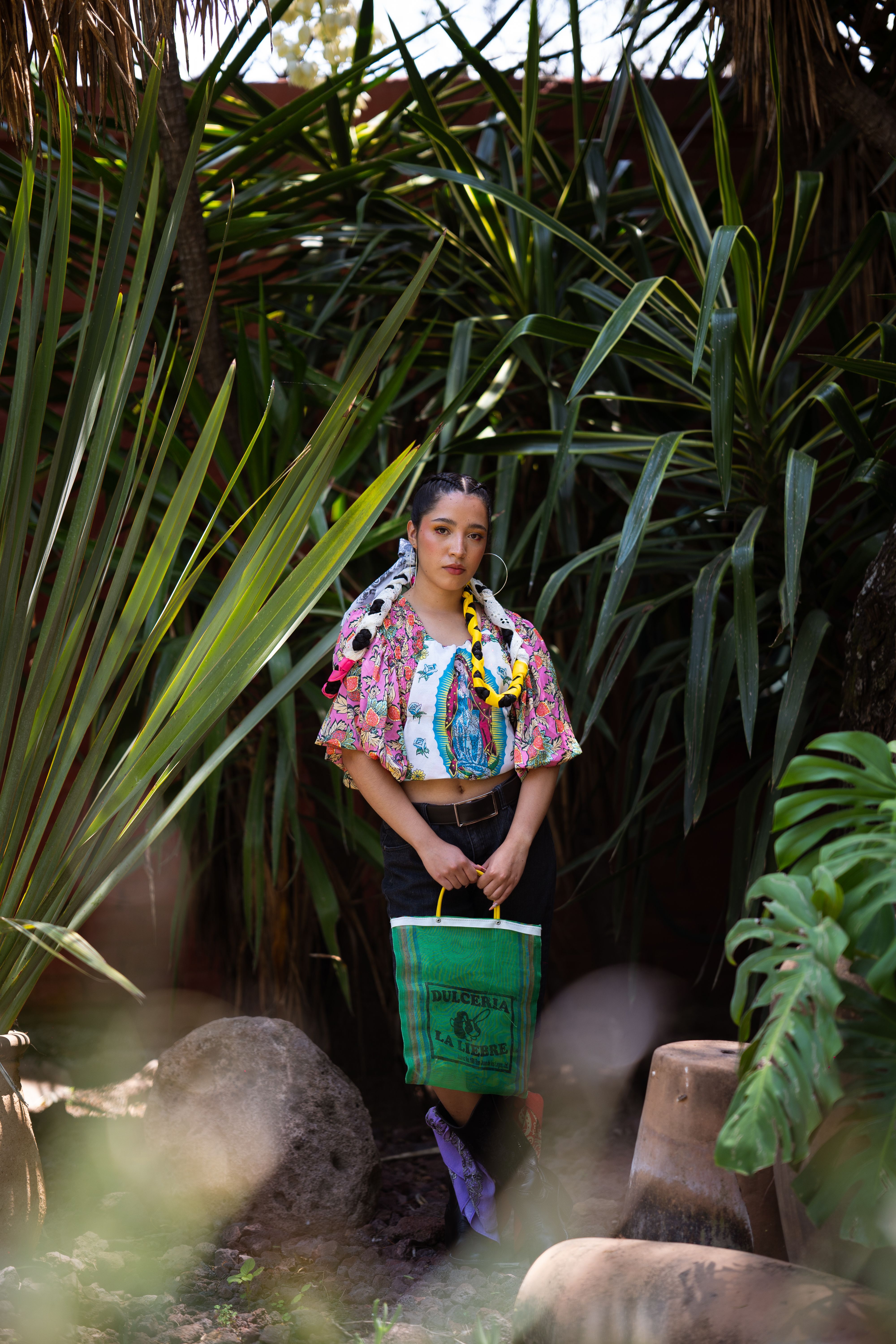 Colorful portrait of a woman in traditional Mexican attire surrounded by lush greenery.
