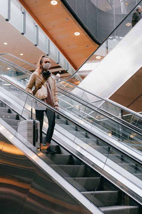 Free Woman With a Face Mask Standing on an Escalator Stock Photo