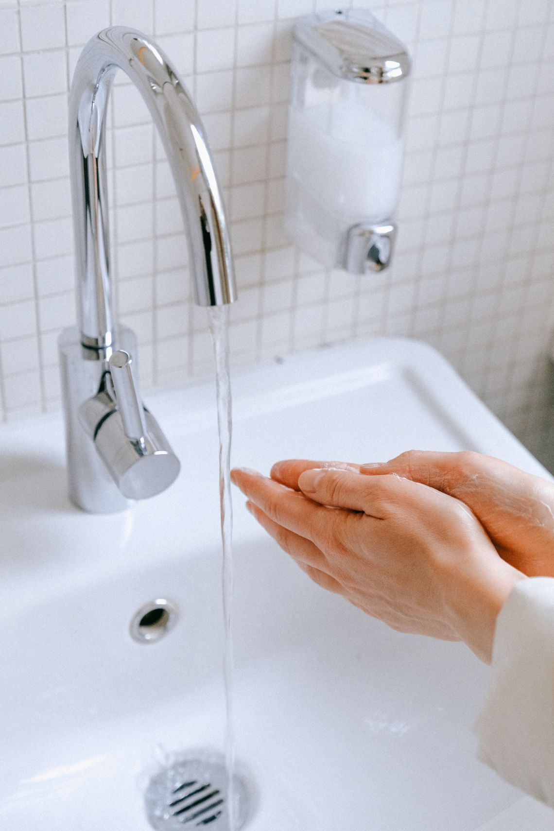 Person washing hands carefully with soap at a bathroom sink