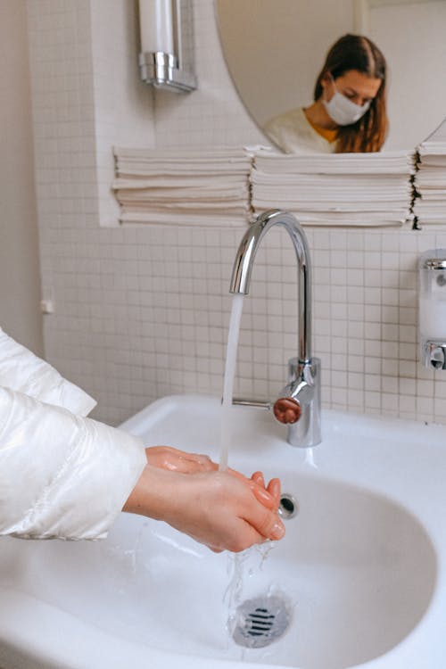 Woman With a Face Mask Washing her Hands
