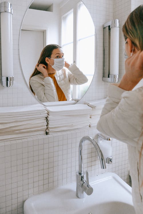 Free Woman With a Face Mask Fixing her Hair Stock Photo