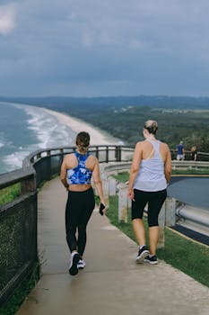 Two women walking on a coastal path with ocean views at Byron Bay, Australia, enjoying fitness and nature.