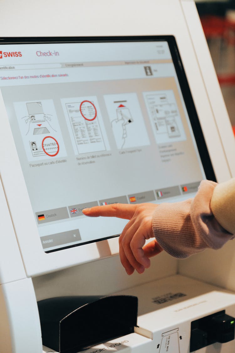 Person In Brown Long Sleeve Shirt Using Self Service Check In Kiosk