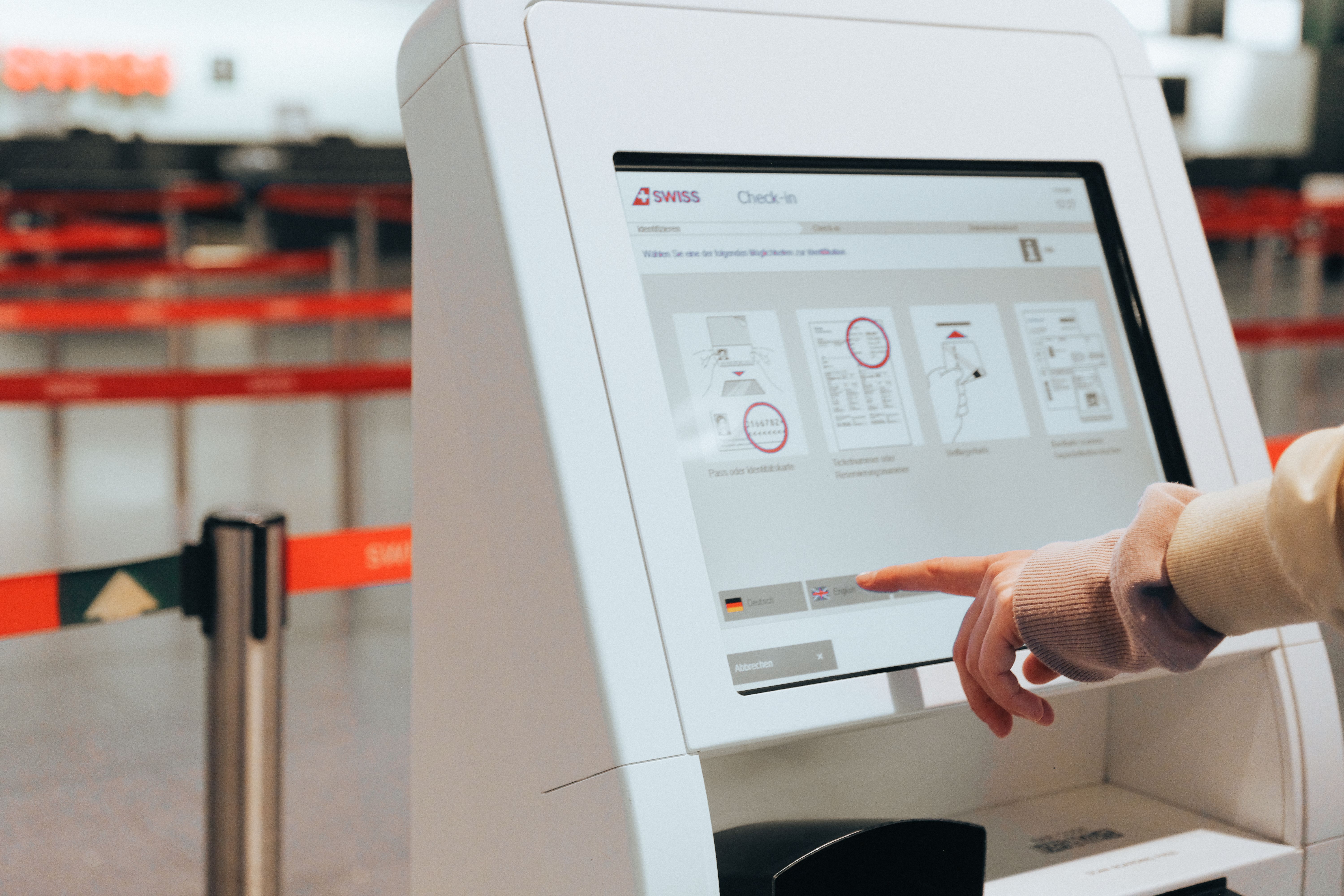 Traveller uses a self-service check-in kiosk at an airport before checking in for a flight