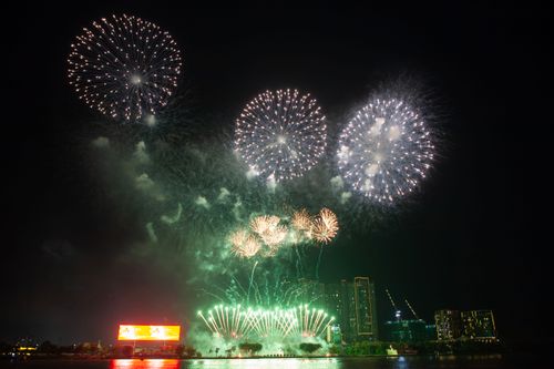 Free Vibrant fireworks burst over a city skyline at night, reflecting on water. Stock Photo