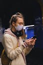 一名女子戴着口罩在地铁站用手机发短信