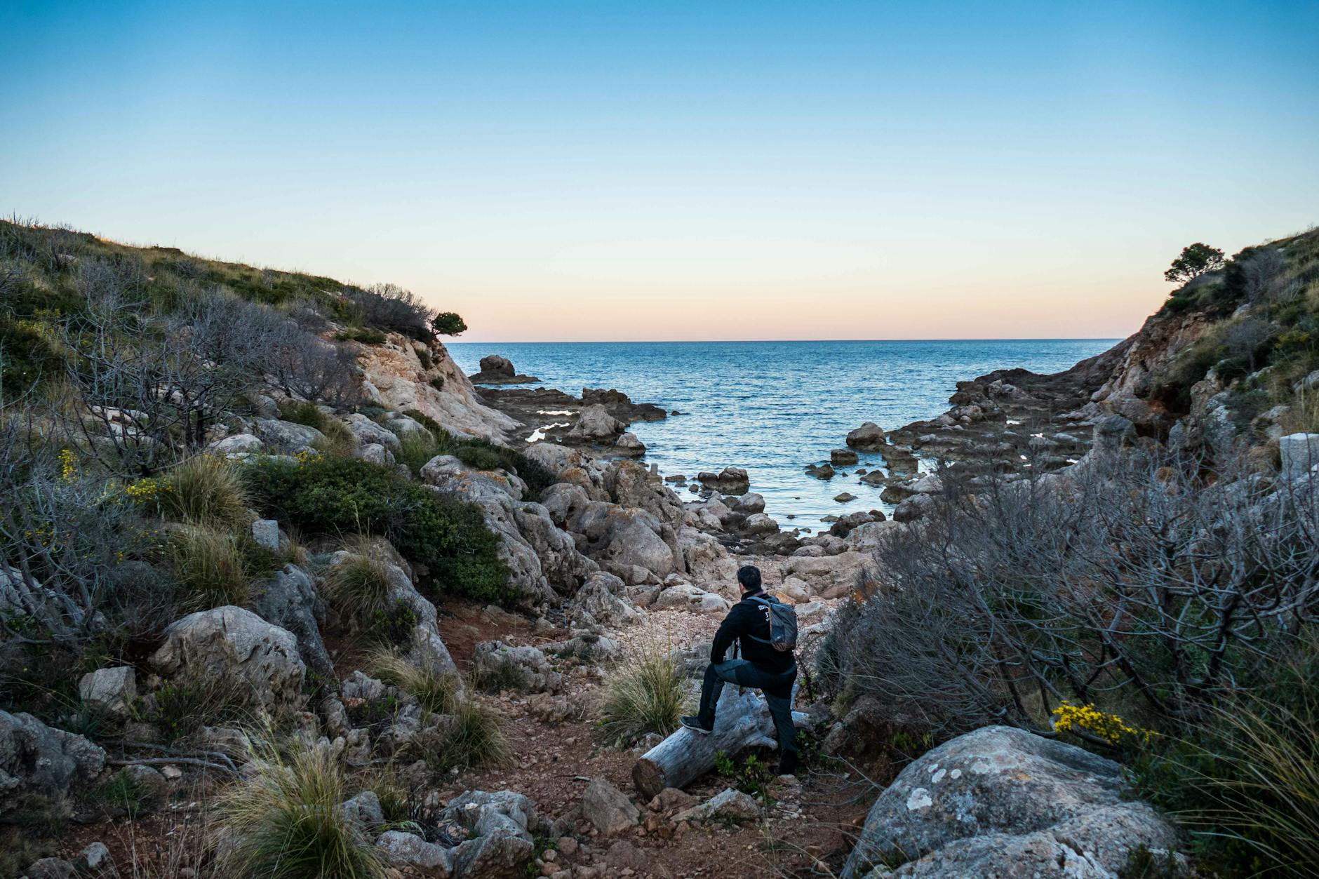 Hiker enjoying a rocky Sardinian beach at sunset