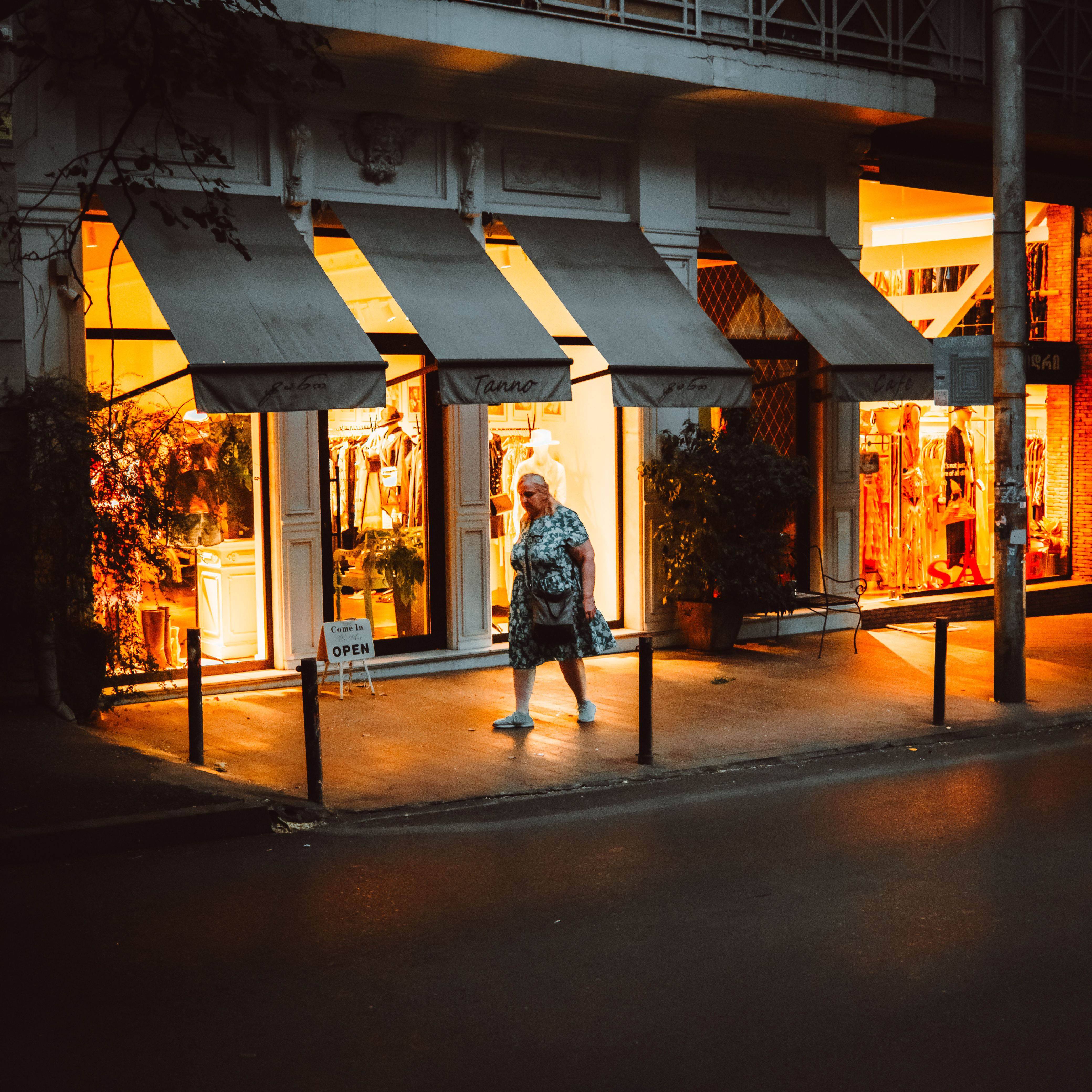 A woman walks past an illuminated boutique in Tbilisi at dusk, creating a warm atmospheric scene.