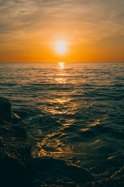 Free Serene sunset view over the ocean in Quảng Trị, Vietnam, with warm golden hues reflecting on the water. Stock Photo