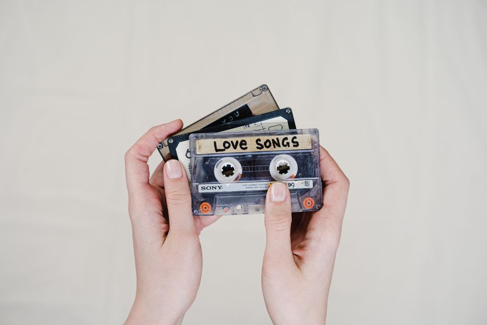 Hands holding a collection of music cassettes