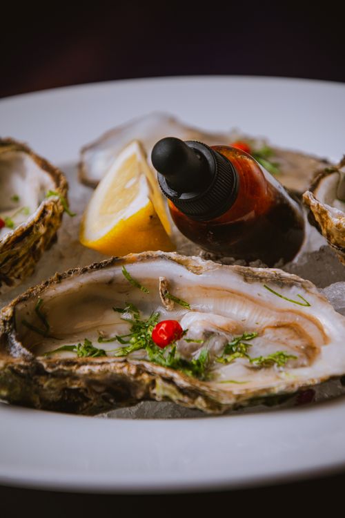 Free Close-up of fresh oysters on ice, garnished with lemon and sauce, perfect for seafood dining. Stock Photo