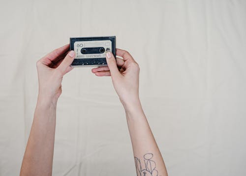 Person Holding Black and Gray Cassette Tape