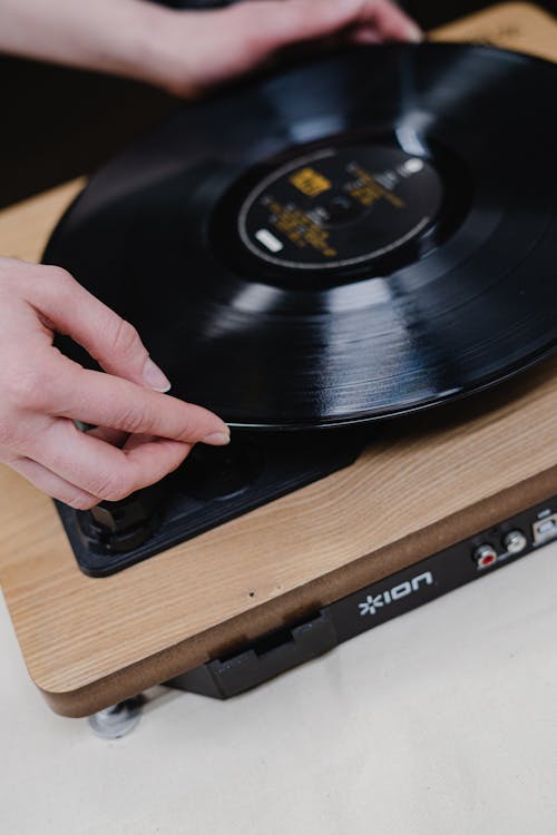 Person Holding Vinyl Record On Vinyl Record Player