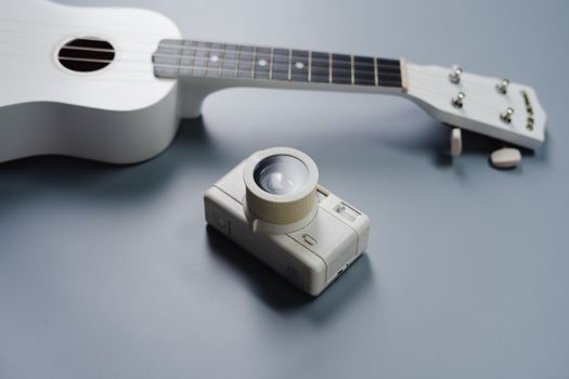 White Guitar and Gold Camera on Gray Table