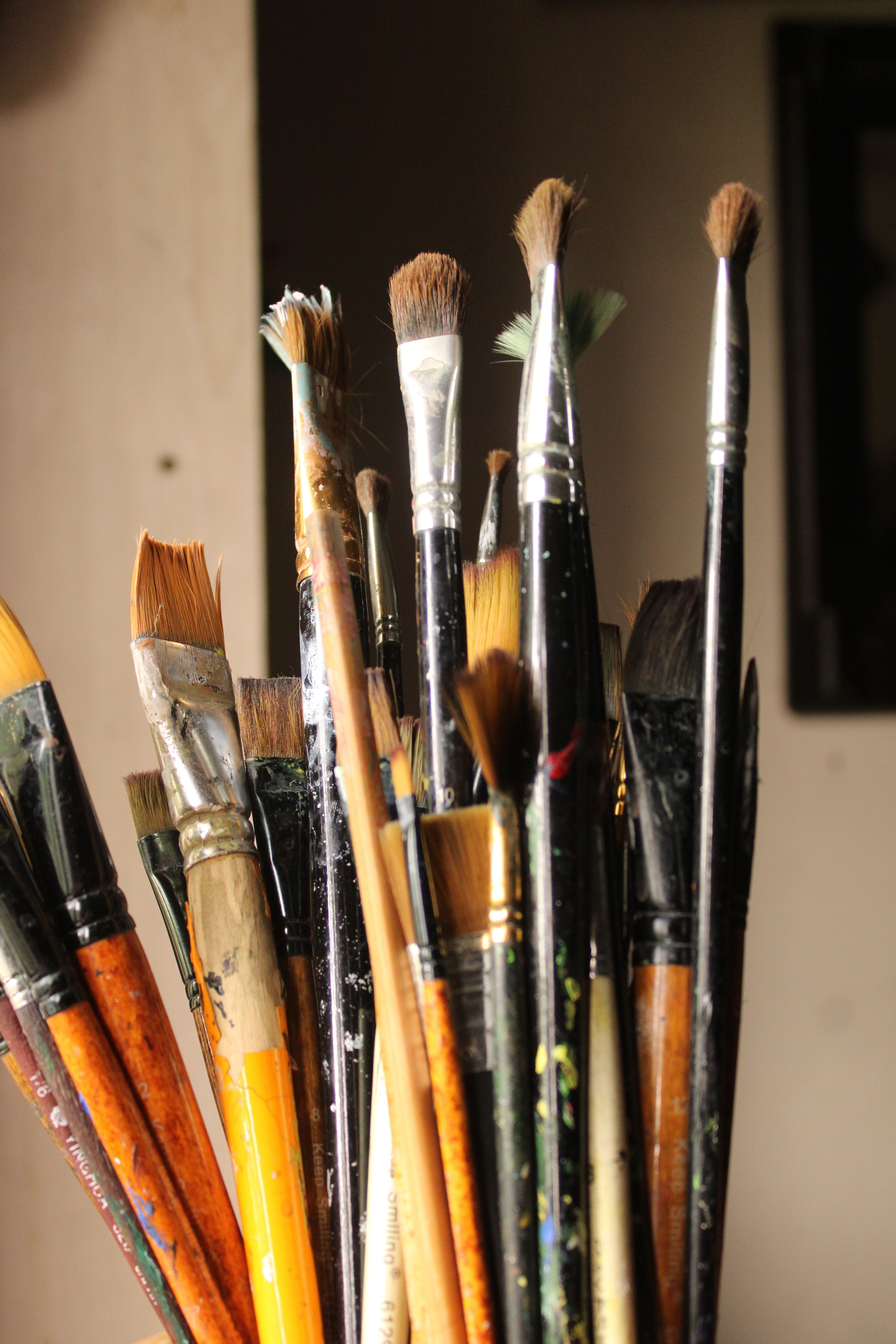 Close-up of various paintbrushes in a holder, showcasing artistic chaos.