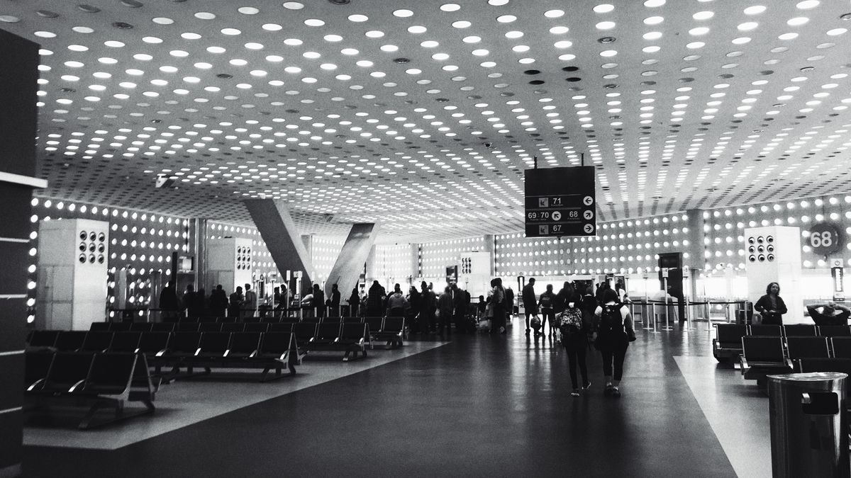 Monochrome image of a busy airport lounge in Mexico City, showcasing modern architecture and travelers.