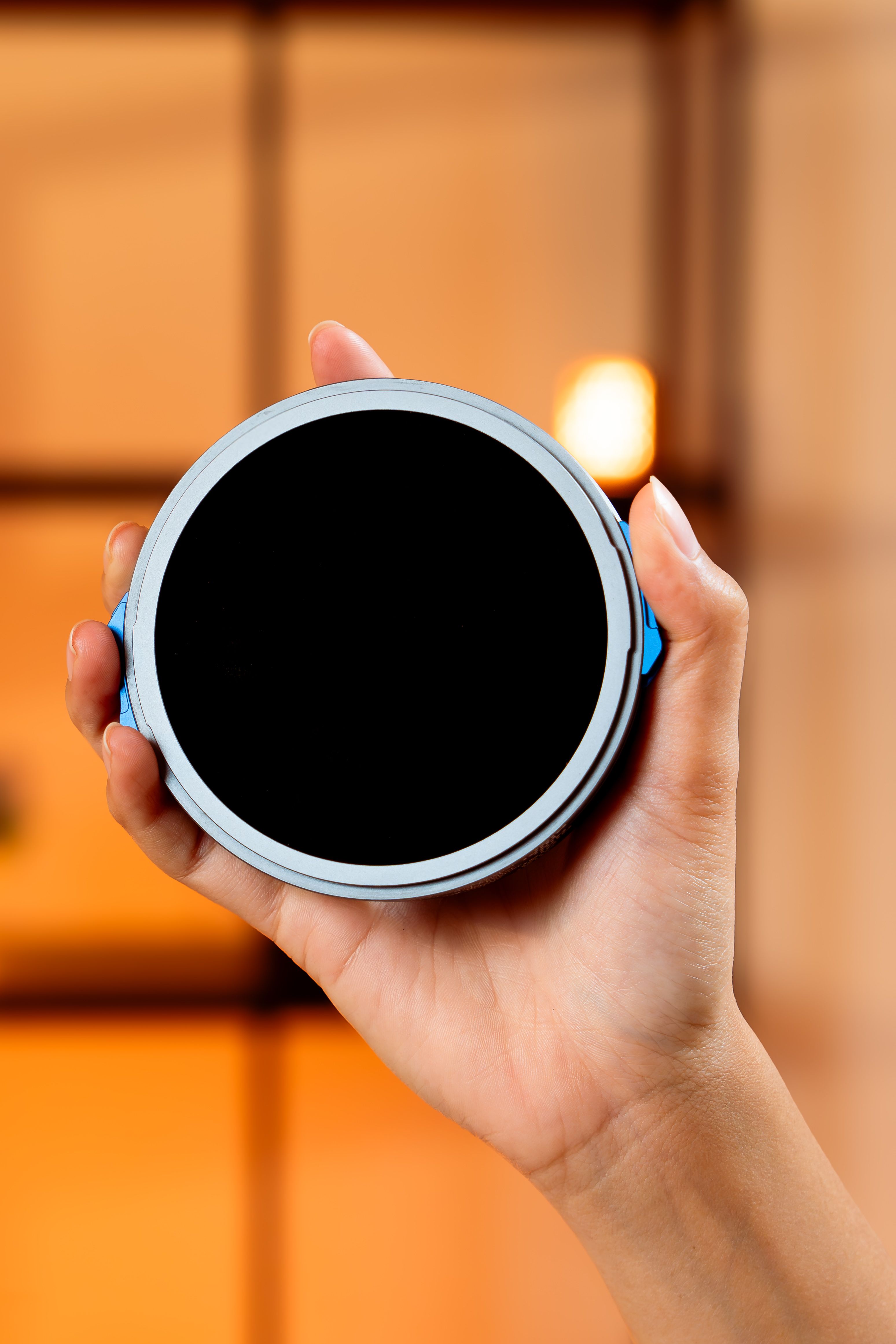 A hand holding a circular black filter in focus, against a blurred background, ideal for tech imagery.