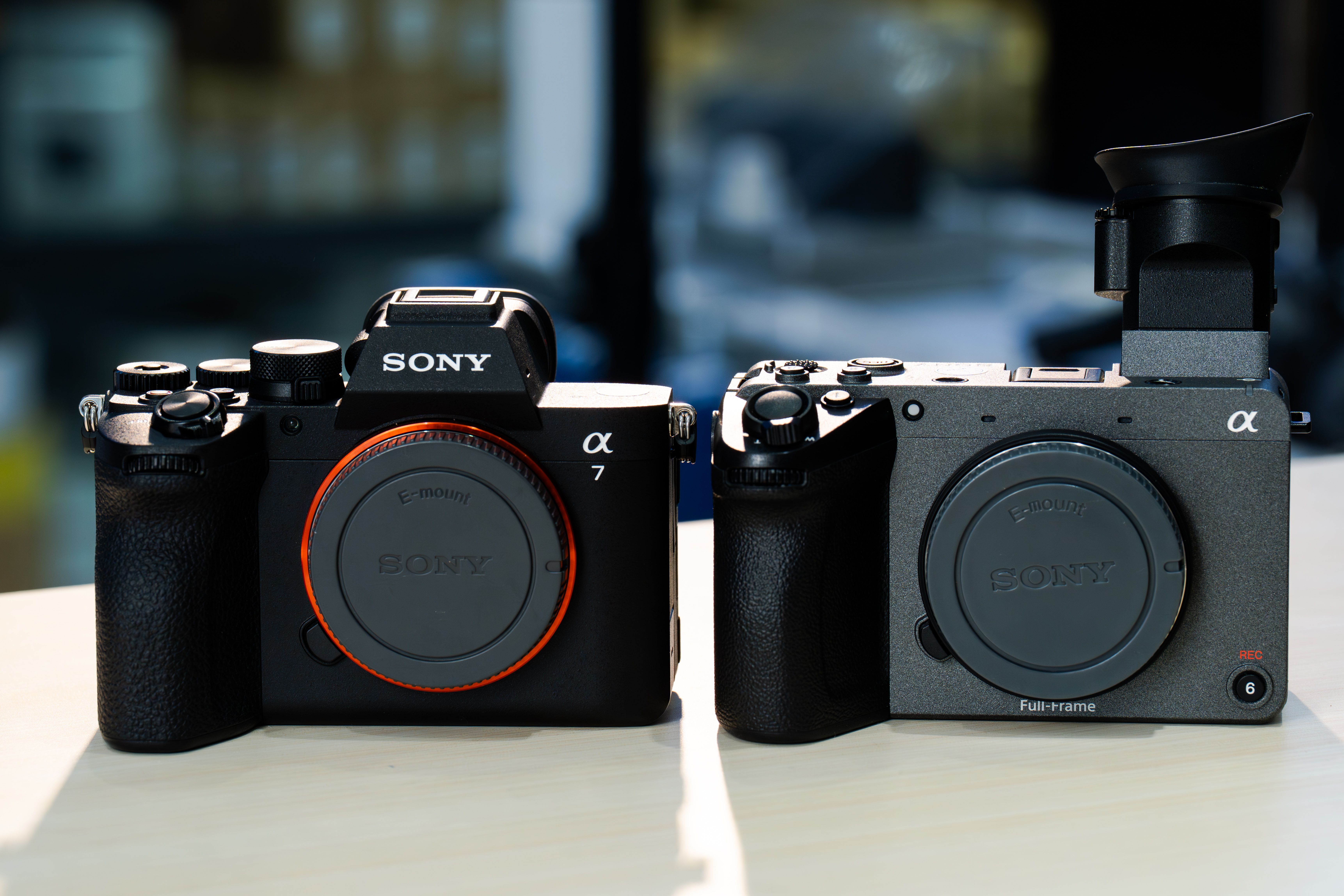 Side-by-side comparison of two modern mirrorless cameras on a table.