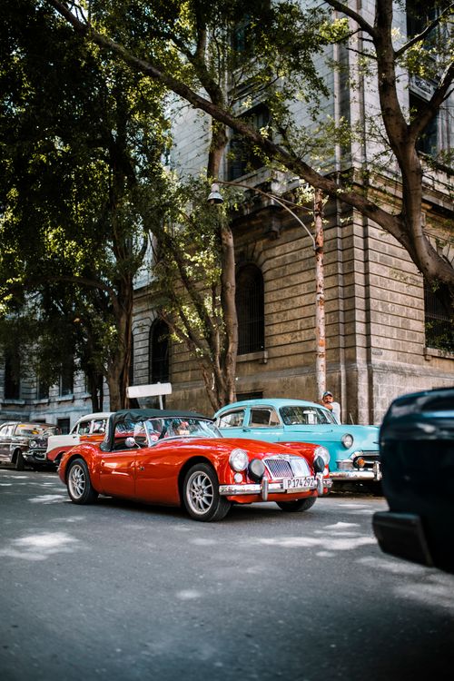 Free Vintage cars cruising down the streets of Havana, Cuba, on a sunny day, capturing the essence of Cuban culture. Stock Photo