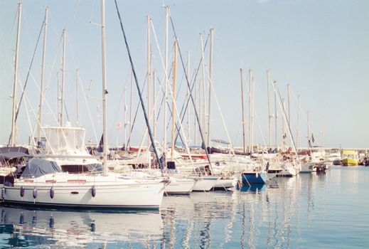 Serene view of sailboats docked in a CN, Spain marina under clear blue skies.
