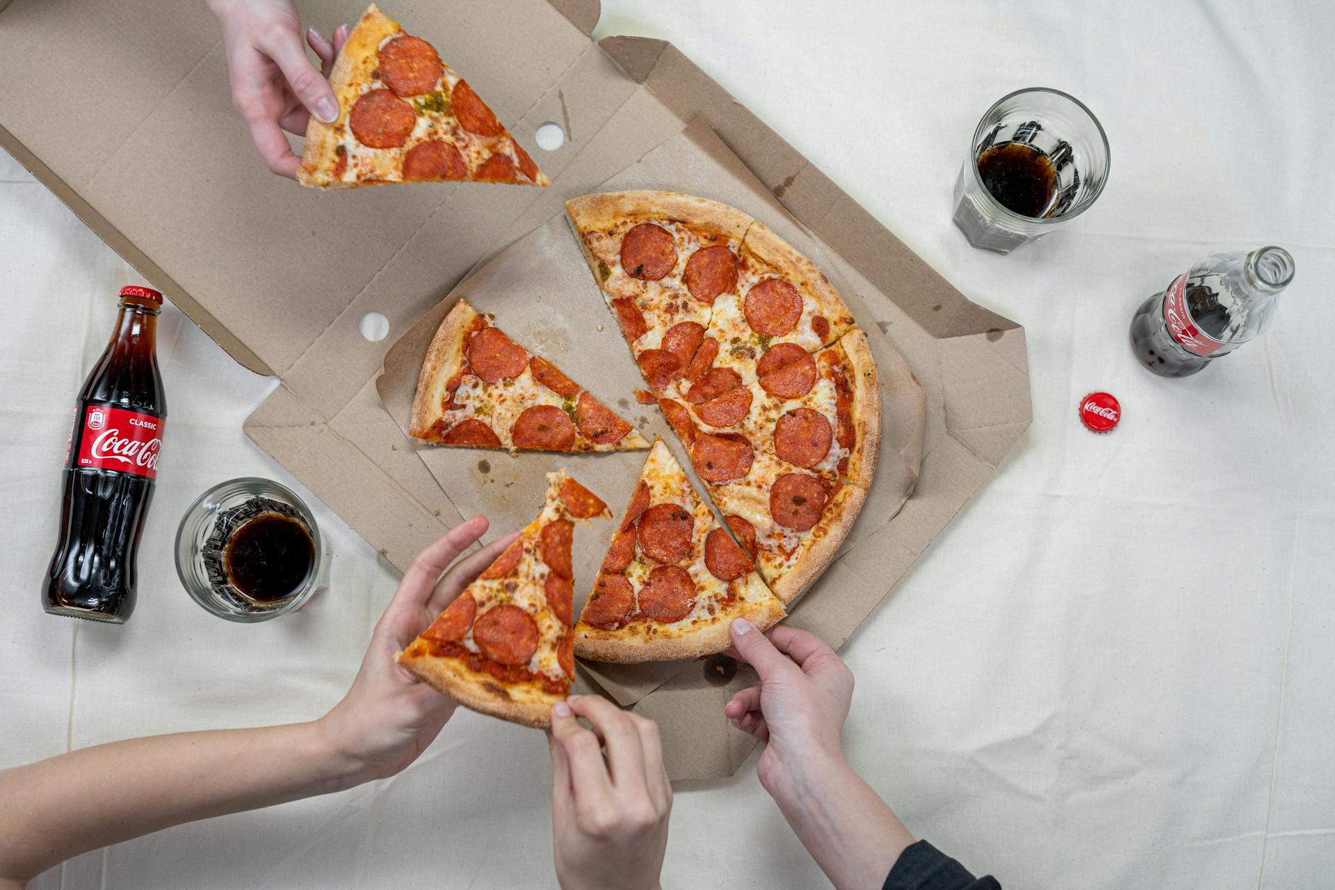 Person Holding Pizza on White Box