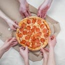 一群朋友正一起享用意大利辣香肠披萨，分享一顿有趣的饭菜