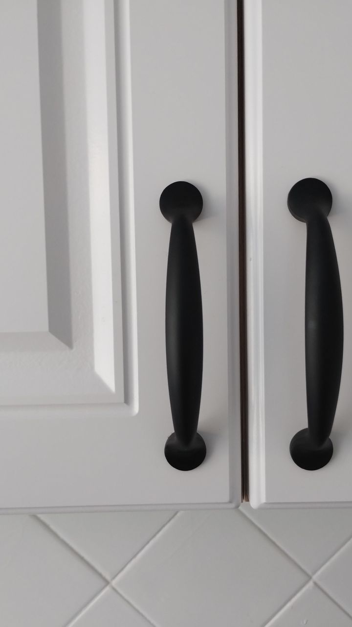 A modern kitchen coffee cabinet with two-tone matte black and brass hardware
