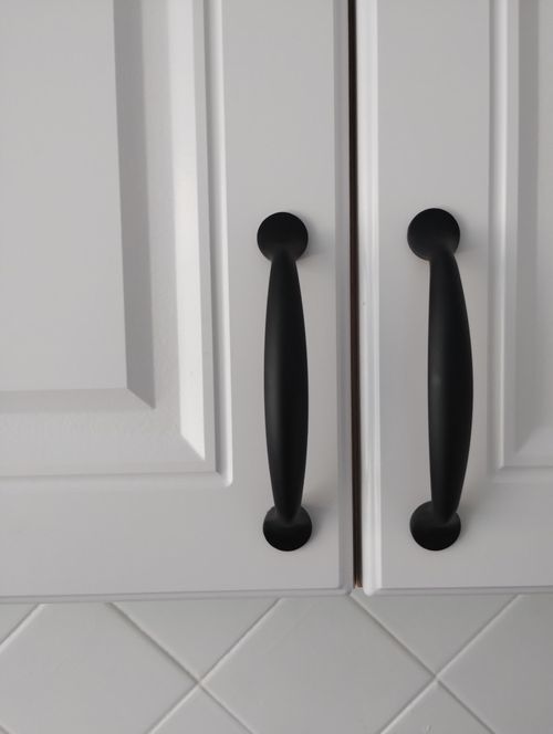 Free Modern black cabinet handles on white kitchen cabinets offer sleek, minimalist design. Stock Photo