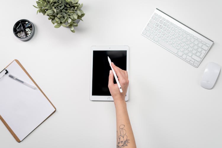 Person Holding White Ipad On White Table