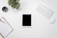 家庭办公桌布置得干净整洁，配备了平板电脑、键盘、鼠标和绿植，以激发灵感