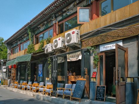 Discover a rustic café with outdoor seating on a sunny street, perfect for a relaxing day out.