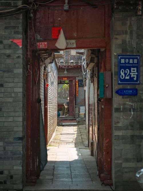Free Charming view through a red door into a Beijing hutong. Traditional Chinese alleyway charm. Stock Photo