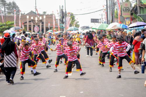 Free Children dressed in vibrant costumes perform a traditional parade dance on a bustling street. Stock Photo