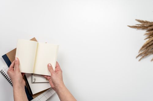 Free Top view of a clean desk with an open notebook, stationery, and dried flowers, perfect for creative work. Stock Photo