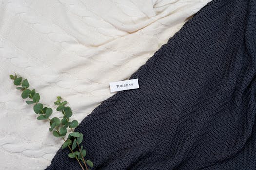 Warm woolen blankets with eucalyptus leaves and a Tuesday note create a cozy flatlay.