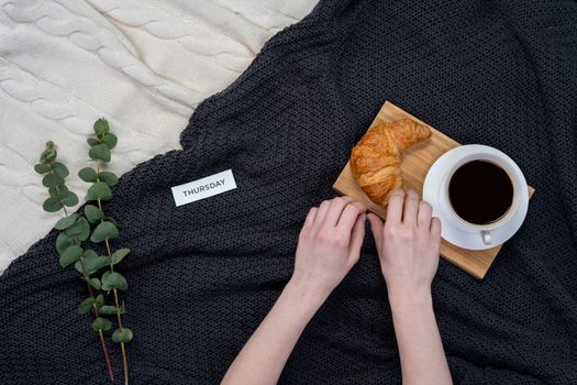 A relaxing setup with black coffee and croissant on a blanket, perfect for a cozy Thursday morning.