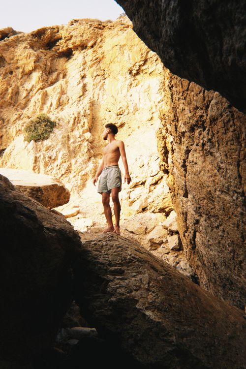 Free A man in shorts exploring sunlit rocky terrain, evoking adventure. Stock Photo