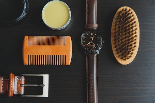 Round Analog Watch Beside A Brush And Hair Wax
