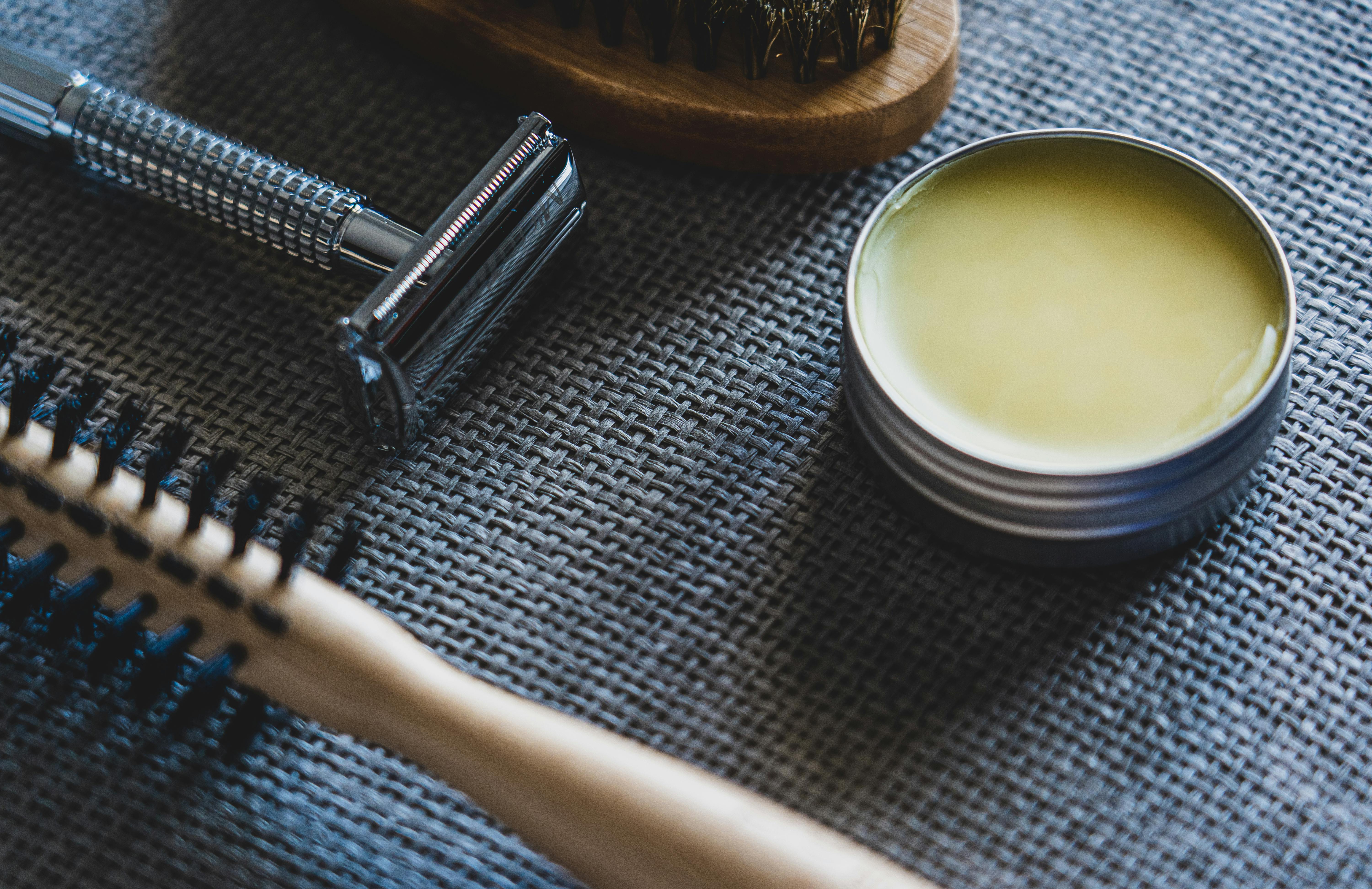 wax in a container beside brushes and shaver